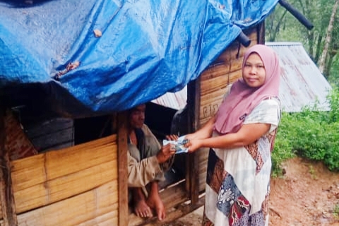 Seorang wanita warga setempat tampak memberikan uang kepada Kakek Asri yang tinggal di rumah reot hidup sebatang kara, fhoto : istimewa.
