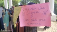 Salah satu pendemo mengangkat kertas manila bertuliskan "Pembatalan Guru Siluman dan Guru Mall Administrasi", fhoto : Istimewa.