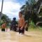 Tampak seorang pengendara mendorong sepeda motor menerobos banjir, dan anak-anak asyik bermain di lokasi banjir, Senin (17/6/2024) fhoto : Naibaho / Wartamandailing.